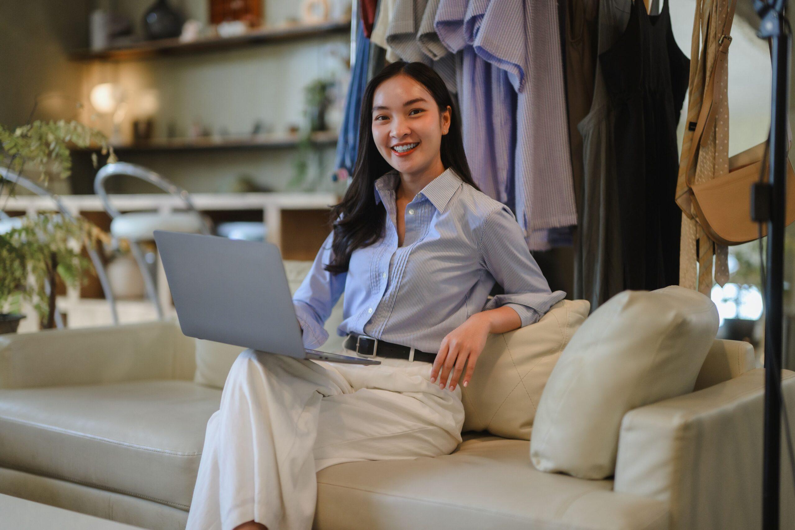 Young fashion content creator sitting relaxed with a laptop on a couch, symbolizing creative freedom through professional support